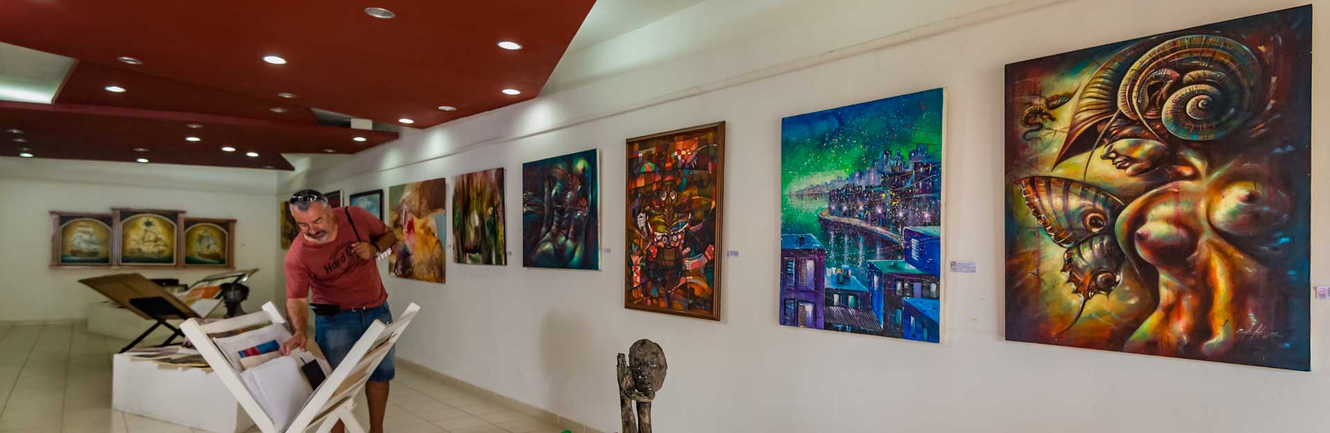 Hombre-recorre-galería-de-exposiciones-de-pinturas-cubanas-CubaTravel